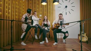 Family coziness in song and music in the evening at home. A family of musicians singing a song together at home. Mata dad dotsya and son sing a song together in the studio. Dad plays the guitar and video