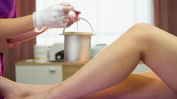 Cosmetologist with a hot wax before wax depilation, close up video