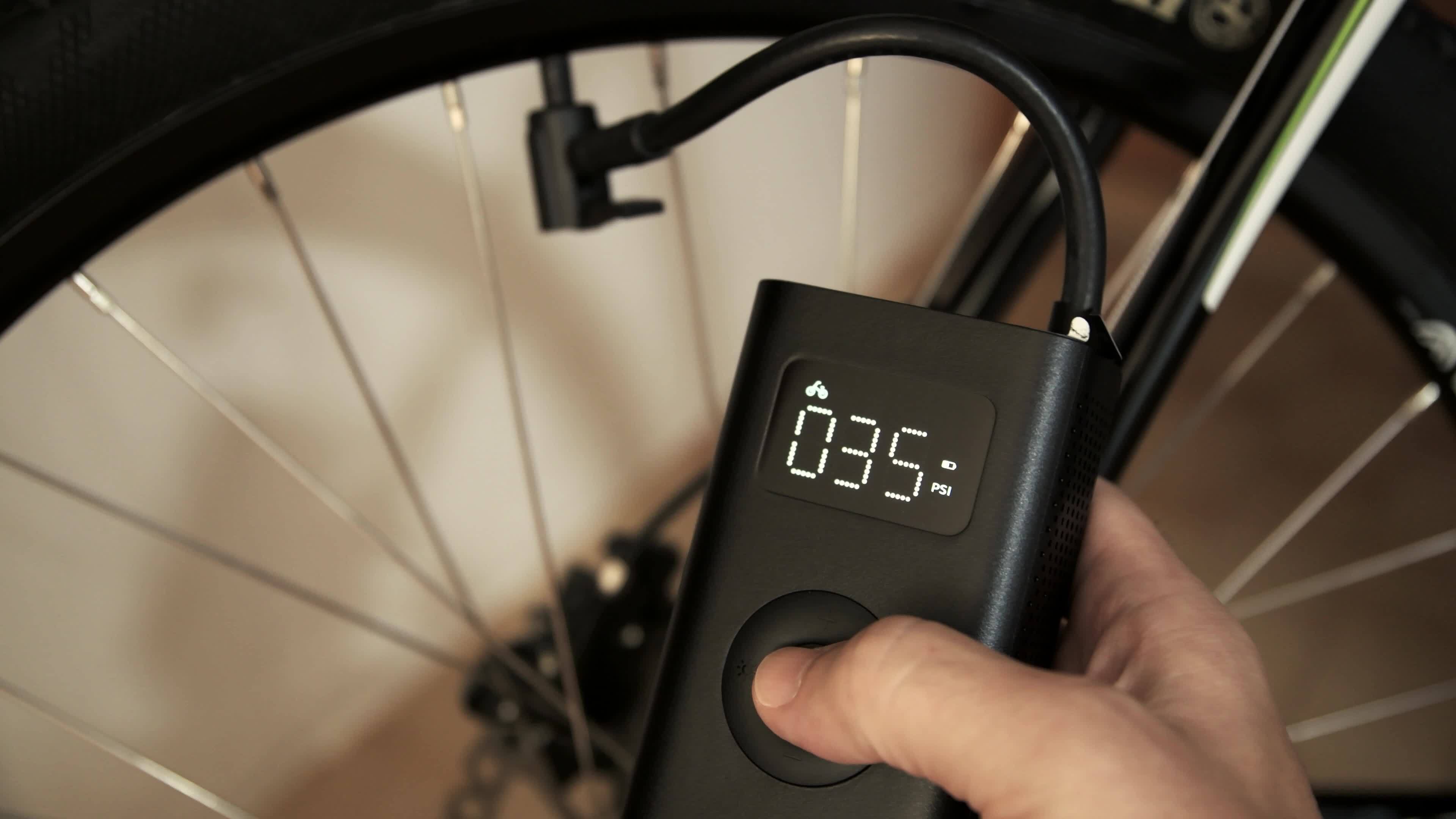 4K footage of man using cordless portable air pump inflating bicycle