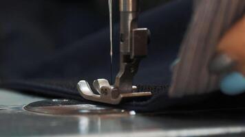Hands of seamstress sewing with a professional machine embroiders sews on red fabric using both sides of the material Concept of Factory Home At Work Professionals. photo
