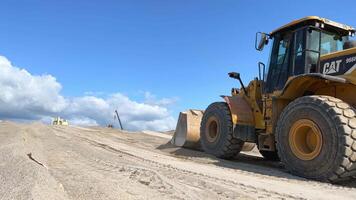 A huge wheel loader with a bucket in front. Heavy machinery is working on the construction site. Tractor shovels sand and gravel with a bucket. Turkey, Mersin. August 29, 2023 video