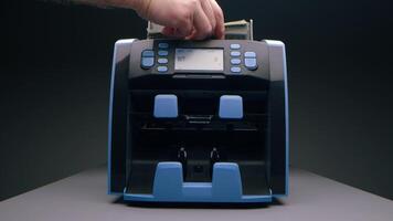 A hand places cash into a bill counter, a modern device designed for quick and efficient counting video