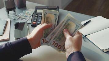 Counting cash at a desk while organizing finances in a home office setting during the afternoon video