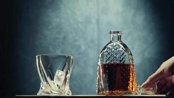 Enjoying whiskey on the rocks with a crystal glass and decanter in a dimly lit setting during a relaxing evening video