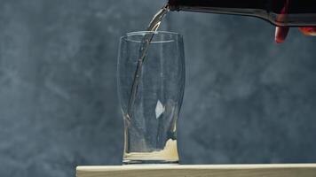 Pouring refreshing beverage into a clear glass on a wooden surface with a textured background video
