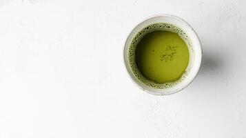 Overhead view of a cup of matcha green tea on a white surface. photo