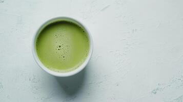 Overhead view of a cup of matcha green tea on a white surface. photo