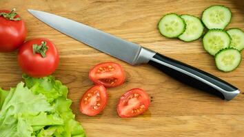 Fresh tomatoes and cucumbers for salad on a wooden board. Preparation of vegetable dietary salad. Close-up. Selective focus. photo