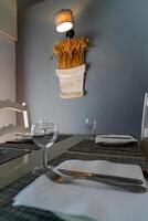 A restaurant table set in natural light, with simple dinnerware, clear glassware, and casually placed napkins, creating a relaxed and welcoming atmosphere for guests. photo