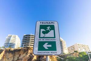 A tsunami evacuation sign at Praia da Rocha, Algarve, Portugal, guiding visitors to safety with clear instructions for emergency situations. photo