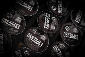Row of dark coffee capsules neatly arranged in a sleek, modern coffee pod holder, creating a minimalist and elegant display photo