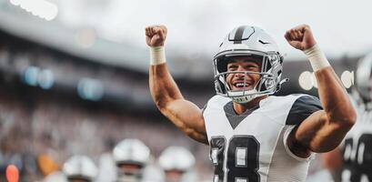 American football player in black and white uniform cheers and raises his fists up photo