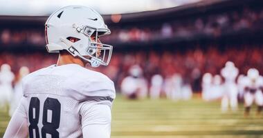 American football player in white uniform stands sideways during match photo