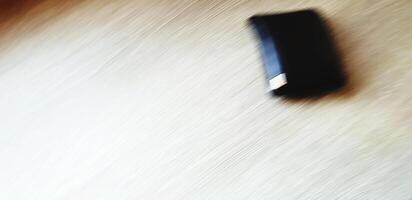 Blurred black or brown leather wallet on light brown wooden table for background. Art, Abstract, Not focus and Movement concept. photo