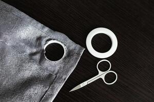 installing eyelets in curtain, cutting out a hole for the grommet with scissors photo