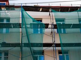 Scaffolding with protective mesh on building, facade restoration photo