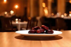 Small elegant plate of rich glossy dates on a dining table, isolated against a warmly lit blurred background, showcasing their natural texture and inviting atmosphere photo