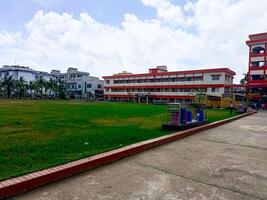 New School Building with Hard Lines and Bright Orange and White Detail and there is a big grass field Infront of the School building photo