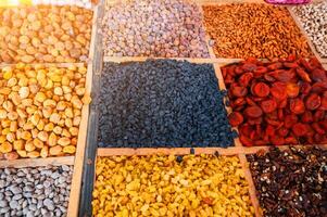 different varieties of dried fruits and nuts on counter of the East Asian food bazaar in Central Asia. Raisins, dried apricots, almonds, walnuts and figs in market stall photo