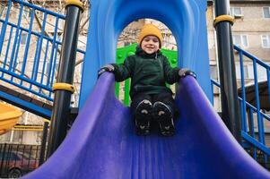 child kid boy playing on slide at playground in the park in autumn photo