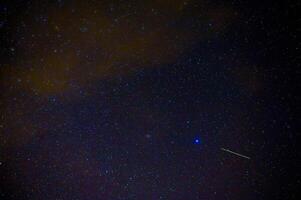 shooting star meteorite comet on background of blue dark starry sky with galaxies and nebulae photo