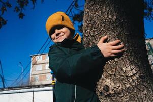 small child kid boy plays and climbs a tree on playground in autumn photo