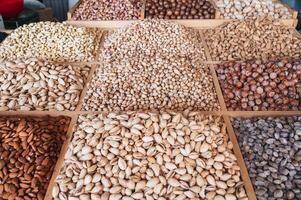 assortment of different nuts on counter at oriental uzbek bazaar. Almonds, pistachios, hazelnuts, macadamia, pecans and cashews photo