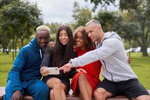 Happy diverse friends taking selfie using smartphone in park photo