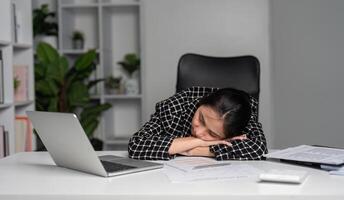 Exhausted Office Worker Sleeping at Desk with Laptop and Documents in Modern Workspace photo