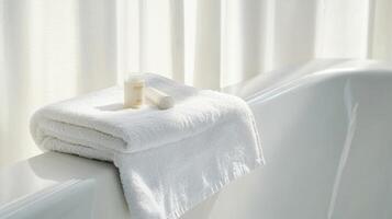 White Towel and Cream on Bathtub Edge Against Pristine Background photo