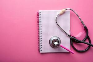Stethoscope and Pulse Heartbeat Notebook on Pink Background presenting a wide angle still life object, stethoscope, still life, heartbeat, pink background, object, notebook photo