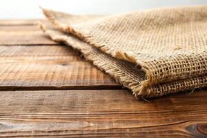 The stock photo features a close up view of the rough and textured burlap fabric placed on a wooden table with a white background creating a forced perspective effect, pattern