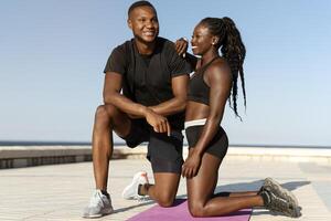 Man and woman sitting near the water and embracing with each other after morning trainings photo