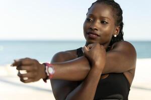 Multiracial female athlete doing relaxing exercise towards the sea photo