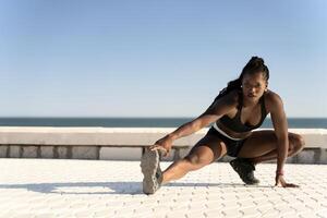 Healthy woman training and doing stretching before exercise on the beach photo