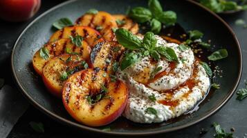 Grilled peaches with creamy burrata and fresh herbs on a plate. photo