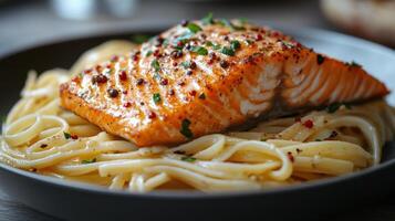 Grilled salmon served over a bed of pasta with herbs and spices. photo