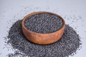 poppy seeds in a wooden bowl on a light background. High quality photo