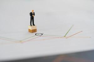 Miniature people stand on a podium with analysis graph business. photo