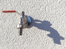 Outdoor Water Faucet with Red Handle Casting Shadow photo