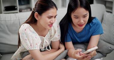 Handheld high angle view shot, Two happy women are enjoying watching something together on mobile phone in living room at home. Happy family time ,Having fun on weekend video