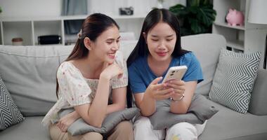 Footage of handheld shot, Two happy women are enjoying watching something together on mobile phone in living room at home. Happy family time ,Having fun on weekend video