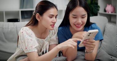 Footage of handheld shot, Two happy women are enjoying watching something together on mobile phone in living room at home. Happy family time ,Having fun on weekend video