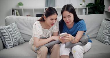 Handheld selective focus shot, Two happy women are enjoying watching something together on mobile phone in living room at home. Happy family time ,Having fun on weekend video