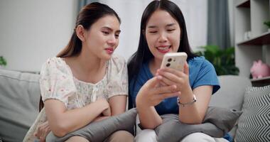 Handheld selective focus shot, Two happy women are enjoying watching something together on mobile phone in living room at home. Happy family time ,Having fun on weekend video