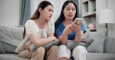 Handheld low angle view shot, Two women are watching something together on mobile phone in living room at home. Happy family time ,Having fun on weekend video