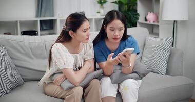 Handheld high angle view shot, Two happy women are enjoying watching something together on mobile phone in living room at home. Happy family time ,Having fun on weekend video