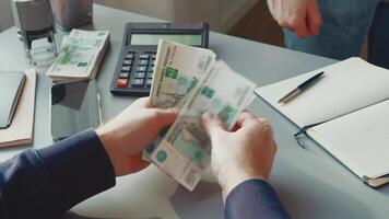 Man hands over cash in business transaction at office desk with calculator, notebook, and documents present video