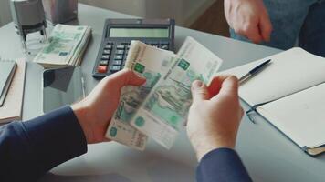 Person exchanging cash at a desk while calculating expenses with a calculator in a business setting video