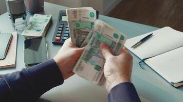Counting cash at a desk with a calculator, notepad, and smartphone in a tidy office setting video